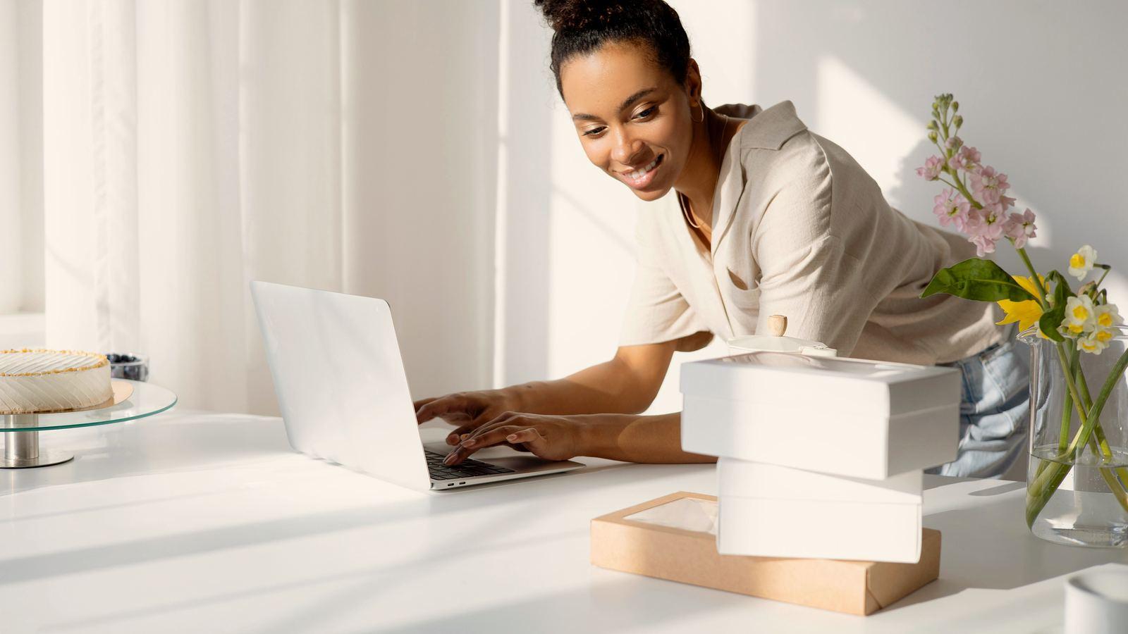 Emprendedora latinoamericana gestionando pedidos de su tienda online desde una laptop entre cajas de envío